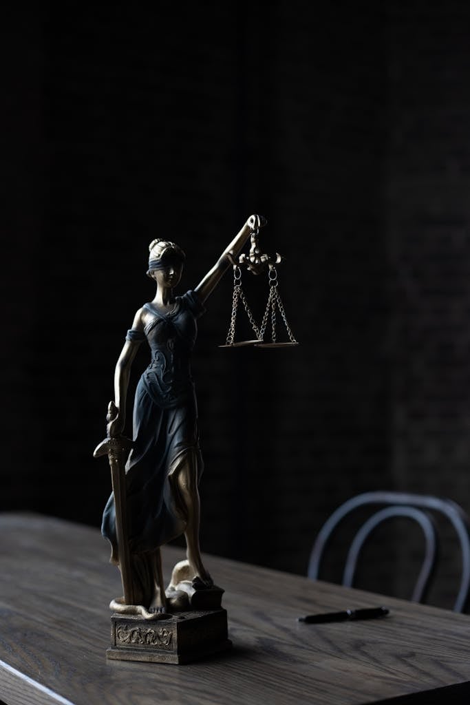 Dramatic lighting on Lady Justice figurine, symbolizing law and fairness.