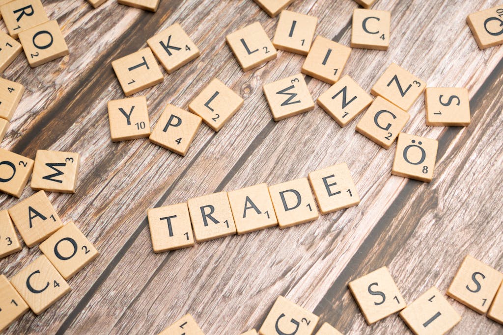 Scrabble letter tiles spelling 'trade' on a wooden surface, illustrating business concepts.