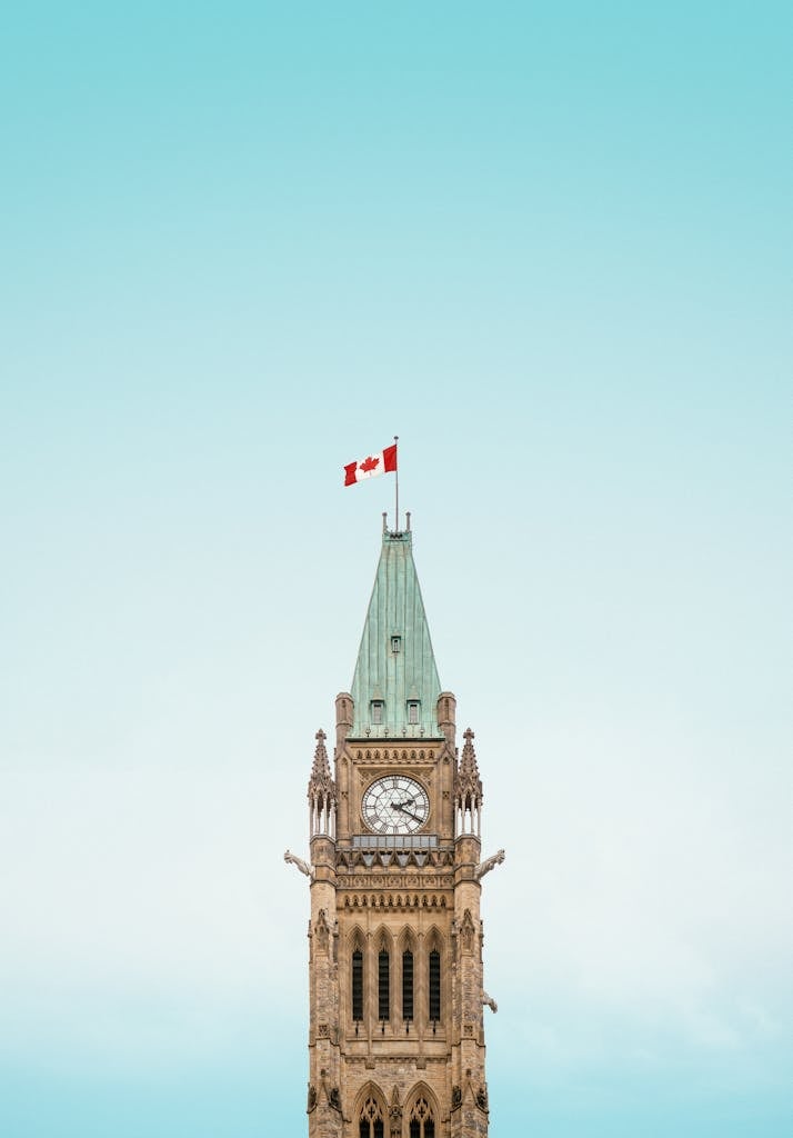 The iconic Peace Tower in Ottawa, Canada, with a clear blue sky and Canadian flag.